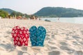 Close up of 2 pair flip flops on sand at tropical beach. Summer holiday concept. Blurred background Royalty Free Stock Photo