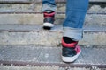 Close-up of a pair of legs walking up some stairs, wearing a pair of jeans and casual red sneakers Royalty Free Stock Photo