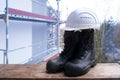 Close-up of pair of new black work boots made of leather with reinforced cape, high top, hardhat on construction site, concept of Royalty Free Stock Photo