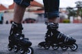 Close up of a pair of roller skates outside. The skates are black and white. Feet with skates on
