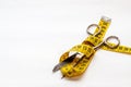 Close up of a pair of scissors resting atop yellow tape on the white background