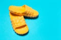 Close-up of pair of yellow slippers on blue background.