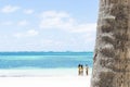 Close up of a palm trunk, turquoise ocean and bikini girls background Royalty Free Stock Photo