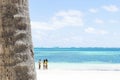 Close up of a palm trunk, turquoise ocean and bikini girls Royalty Free Stock Photo