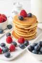 Close-up of pancakes in stack with blueberries and raspberries on table and white background, selective focus Royalty Free Stock Photo