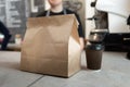 Close-up of a paper bag and a glass of hot espresso coffee stands on a table in a cafe or bar. Order for delivery at the Royalty Free Stock Photo