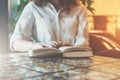 Close-up of paper book, notebook, diary on table in cafe. Businesswoman in white shirt sitting at table and reading book Royalty Free Stock Photo