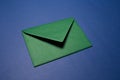 Close-up of paper envelope of green color isolated on background of textured blue wall.