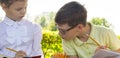 Close-up, in the park, in the fresh air, schoolchildren doing homework, a boy and a girl are peeping from each other`s decision Royalty Free Stock Photo