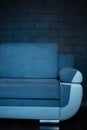 Close-up of part of blue sofa on the background of black brick wall.