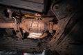 Close-up on the part of the bottom of the car from the front of the exhaust pipe and the catalyst disassembled during the repair