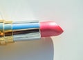 Close-up of a part of a golden tube of lipstick on a white background