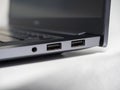 Close-up of a part of a laptop standing on a light background. Large USB ports on the laptop. Open laptop