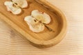 Close-up part of oblong wooden plate with apple chips on wooden background