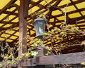 Close-up of part of an open summer building. Antique decorative metal lantern, wooden beams twined.