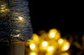 Close-up of part of a silver Christmas tree, with defocused lights from a garland in the background. Concept of greeting Christmas Royalty Free Stock Photo