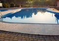 Close-up of a part of swimming pool with a stainless steel ladder and blue water on sunset. Summer vacation, holidays, relax Royalty Free Stock Photo