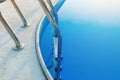 Close-up of a part of swimming pool with a stainless steel ladder and blue water on sunset. Summer vacation, holidays, relax Royalty Free Stock Photo