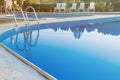 Close-up of a part of swimming pool with a stainless steel ladder and blue water on sunset. Summer vacation, holidays, relax Royalty Free Stock Photo