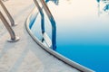 Close-up of a part of swimming pool with a stainless steel ladder and blue water on sunset. Summer vacation, holidays, relax, Royalty Free Stock Photo