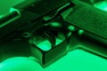 Close up partial view of an automatic hand gun illuminated in green light Royalty Free Stock Photo