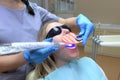 Close-up partial view of dentist using dental curing UV lamp on teeth of patient Royalty Free Stock Photo