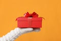 Close-up partial view of man in sweater holding red gift box on yellow background.Gift giving concept Royalty Free Stock Photo