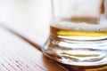 Close-Up Of Partially Finished Cold Glass Of Beer With Frothy Foam And Bubbles On Rough Wooden Table