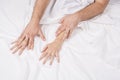 Close up of passionate couple hold hands during making intense love in bedroom, lovers enjoy hot sex on white sheet Royalty Free Stock Photo