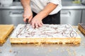 Close-up of a pastry chef cutting a large cake in portions at pastry shop.