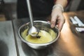 Close-up of a pastry chef mixing icing with food coloring with a hand blender. High angle shot.