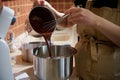 Close-up pastry chef pouring melted chocolate into a planetary mixer bowl, mixing it with cream or whipped egg whites Royalty Free Stock Photo