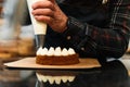 Close-up of a pastry chef`s hands filling a cream cake