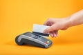 Close-up of payment machine buttons with human hand holding plastic card near by on yellow background Royalty Free Stock Photo