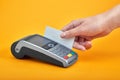 Close-up of payment machine buttons with human hand holding plastic card near by on yellow background Royalty Free Stock Photo