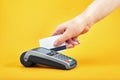 Close-up of payment machine buttons with human hand holding plastic card near by on yellow background Royalty Free Stock Photo