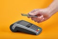 Close-up of payment machine buttons with human hand holding plastic card near by on yellow background Royalty Free Stock Photo