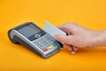 Close-up of payment machine buttons with human hand holding plastic card near by on yellow background Royalty Free Stock Photo