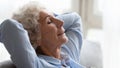 Close up peaceful older woman relaxing on cozy sofa