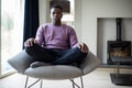 Close Up Of Peaceful Teenage Boy Meditating Sitting In Chair At Home