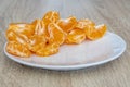 Close up of pealed mandarin peaces on white plate, wooden desk surface