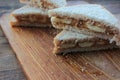 Close-up of Peanut butter banana sandwiches on wooden background. Slices of whole wheat bran bread with peanut paste on cutboard Royalty Free Stock Photo