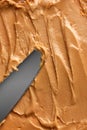 Close-up of peanut butter with smooth, creamy texture. Light brown color with few small swirls made with knife