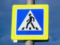 Close-up pedestrian crossing sign with bright yellow frame on cloudy dark blue sky background Royalty Free Stock Photo
