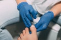 Close-up pedicure process in salon. Foot care treatment and nail. Removing dirt under the nails. Master in blue gloves makes pedic Royalty Free Stock Photo