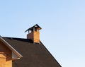 Close up of peeled brick chimney on the roof under blue sky