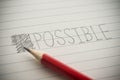Close up pencil handwriting impossible change to possible via strikethrough on notepad background. Royalty Free Stock Photo
