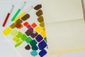 Close-up of pens of different bright colors, multicolored stains of colors on light background of paper texture, top