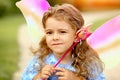 Close up pensive little elf girl in a blue dress with wings in the park Royalty Free Stock Photo