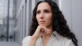 Close up pensive thoughtful puzzled Caucasian Hispanic thoughtfully girl woman with curly hair standing outdoors sad